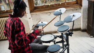 Young man in re check shirt playing a Roland TD-02KV electronic drum set